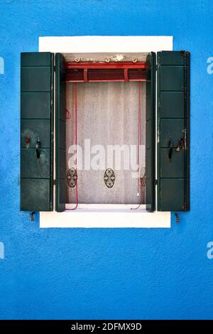 Fenêtre avec obturateur vert ouvert sur mur bleu. Italie, Venise, île de Burano. Banque D'Images
