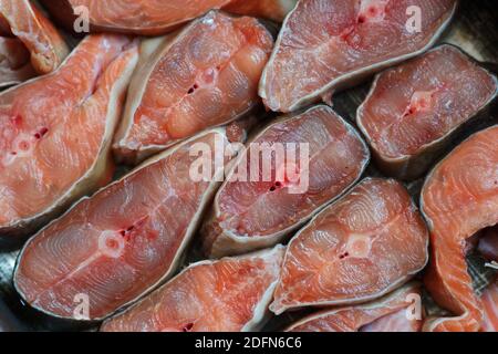 Des tranches de poisson rouge sont disposées en rangée. Résumé du saumon kéta ou saumon rose en gros plan. Banque D'Images