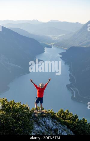 Mountaineer, jeune homme met ses bras dans l'air, vue sur le paysage de montagne, vue du sommet du Baerenkopf à l'Achensee, Karwendel, Tyrol Banque D'Images