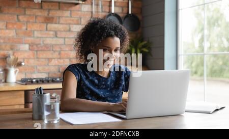 Bonne jeune femme d'affaires multiraciale d'origine africaine travaillant sur ordinateur. Banque D'Images