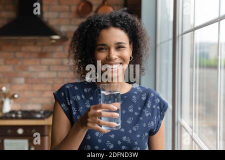 Bonne jeune femme ethnique multiraciale tenant un verre d'eau. Banque D'Images