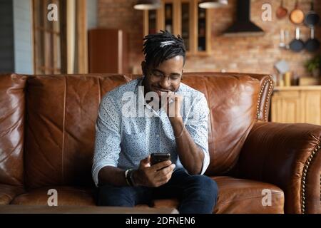 Jeune homme ethnique africain souriant utilisant un smartphone. Banque D'Images