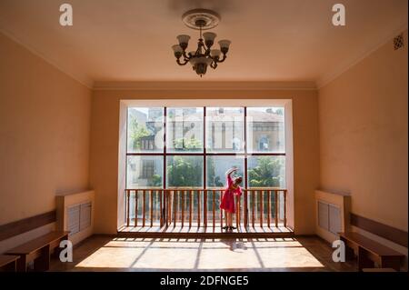 école de ballet russe concept de danse de petite fille près de la fenêtre dans le hall avec une rue derrière la fenêtre Banque D'Images