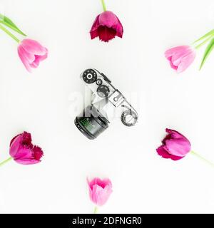 Appareil photo rétro et fleurs roses sur blanc. Flat Lay, vue de dessus Banque D'Images