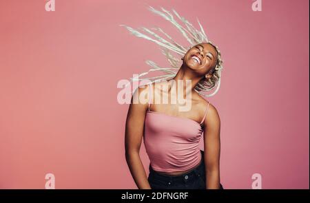 Portrait d'une femme souriante dansant sur fond rose. Femme de bonne humeur dansant avec des cheveux volants. Banque D'Images