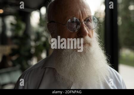 Vieil homme attentionné avec une barbe blanche qui regarde loin. Homme âgé avec tristesse concept. Banque D'Images