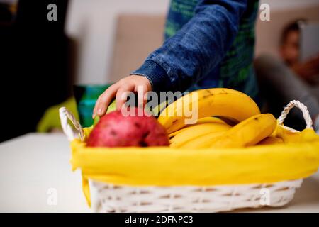 Gros plan d'un garçon mangeant de la pomme à partir d'un fruit sain panier Banque D'Images