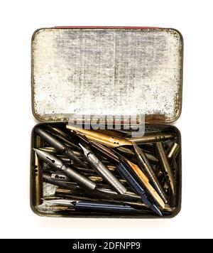 Photo d'une ancienne boîte en étain pleine de vieux stylo et de pointes d'encre pour la calligraphie musique partition écriture sur un fond blanc Banque D'Images