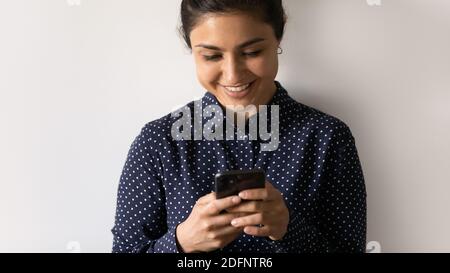 Prise de vue en studio courte d'une femme indienne heureuse à l'aide d'un smartphone