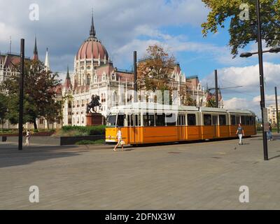 Budapest, Hongrie - 24 septembre 2020 : quelques personnes marchent sur la magnifique place Kossuth en face du tramway jaune et du Parlement hongrois blanc Banque D'Images