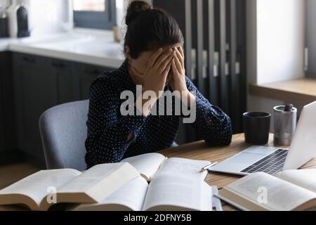 Femme indienne fatiguée étudiante s'asseoir à la maison bureau sentant mal de tête Banque D'Images