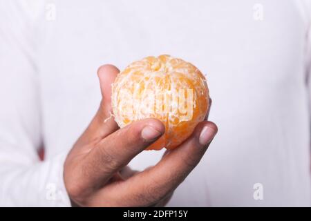 gros plan de l'homme mangeant une tranche d'orange Banque D'Images