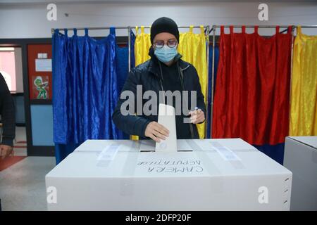 Bucarest, Roumanie. 6 décembre 2020. Un électeur portant un masque de visage émet un bulletin de vote dans un bureau de vote à Bucarest, Roumanie, le 6 décembre 2020. Dans le cadre de mesures de protection spéciales, plus de 18 millions de Roumains devraient voter dimanche pour élire un nouveau Parlement bicaméral pour les quatre prochaines années. Credit: Gabriel Petrescu/Xinhua/Alay Live News Banque D'Images