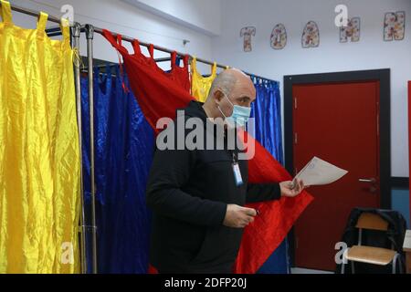 Bucarest, Roumanie. 6 décembre 2020. Un homme portant un masque de visage sort d'un stand pour voter dans un bureau de vote à Bucarest, Roumanie, le 6 décembre 2020. Dans le cadre de mesures de protection spéciales, plus de 18 millions de Roumains devraient voter dimanche pour élire un nouveau Parlement bicaméral pour les quatre prochaines années. Credit: Gabriel Petrescu/Xinhua/Alay Live News Banque D'Images