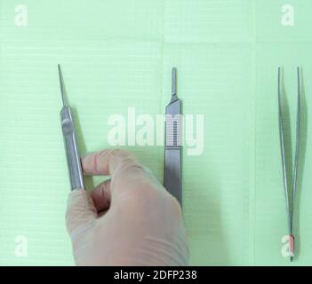 Gros plan de la main du podiatre portant des gants et prenant une gouge de la table de travail. Vous pouvez voir plus d'outils podiatres sur la table Banque D'Images