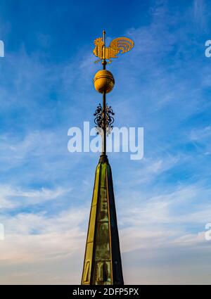 Grande girouette dorée montée sur le sommet d'une tour d'église massive. Gros plan aérien. Banque D'Images