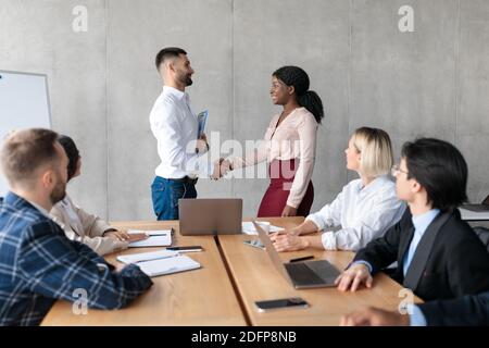 Homme d'affaires et femme d'affaires qui se sont mis à la main après les négociations pendant la réunion au bureau Banque D'Images