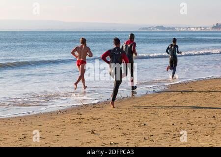 Bournemouth, Dorset, Royaume-Uni. 6 décembre 2020. Météo au Royaume-Uni : les plages sont occupées tandis que les gens se dirigent vers le bord de mer pour faire de l'exercice et de l'air frais et pour profiter du soleil sur une journée froide, mais ensoleillée sur les plages de Bournemouth. Bournemouth Lifeshirsards dans l'entraînement en courant le long de la mer. Crédit : Carolyn Jenkins/Alay Live News Banque D'Images