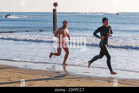 Bournemouth, Dorset, Royaume-Uni. 6 décembre 2020. Météo au Royaume-Uni : les plages sont occupées tandis que les gens se dirigent vers le bord de mer pour faire de l'exercice et de l'air frais et pour profiter du soleil sur une journée froide, mais ensoleillée sur les plages de Bournemouth. Bournemouth Lifeshirsards dans l'entraînement en courant le long de la mer. Crédit : Carolyn Jenkins/Alay Live News Banque D'Images