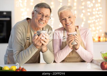 Bon couple Senior boire un café pour fêter Noël assis dans la cuisine Banque D'Images