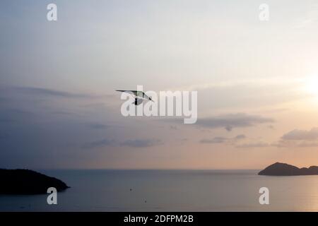 Deltaplane à moteur volante au-dessus de la mer parmi les îles tropicales au coucher du soleil Banque D'Images