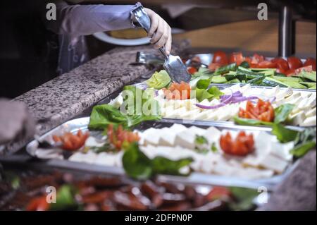 Image de faible profondeur de champ (mise au point sélective) avec la main d'un enfant cueillant des légumes et du fromage à partir d'un buffet ouvert. Banque D'Images