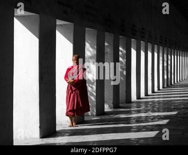 Moine Bouddhiste Novice debout dans l'Est de l'escalier, la pagode de Shwezigon Bagan Nyaung U,, Myanmar (Birmanie), l'Asie en février - les colonnes et les ombres Banque D'Images