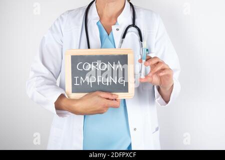 Un médecin tenant un tableau de surveillance avec la vaccination corona écrit dessus elle et une seringue Banque D'Images