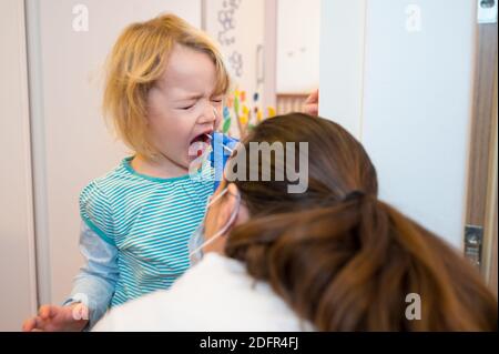 Fille blonde ayant un écouvillon oropharyngé inséré pour la détection de covid 19. Banque D'Images