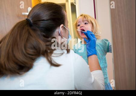 Fille blonde ayant un écouvillon oropharyngé inséré pour la détection de covid 19. Banque D'Images