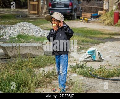 Le petit Tajik joue sur une voiture à Hisor, au Tadjikistan Banque D'Images