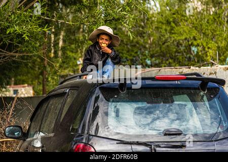 Le petit Tajik joue sur une voiture à Hisor, au Tadjikistan Banque D'Images