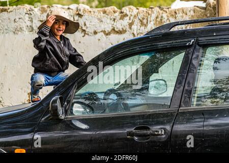 Le petit Tajik joue sur une voiture à Hisor, au Tadjikistan Banque D'Images