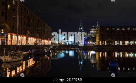 Trois grâces et les lumières festives se reflètent dans l'Albert Dock en décembre 2020. Banque D'Images