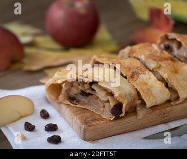 Un strudel de pomme sur bois et arrière-plan de table décoré de pommes et de feuilles d'automne, chute encore la vie composiiton, vue d'angle Banque D'Images