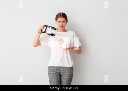 Jeune femme stressée avec taches de café sur son t-shirt arrière-plan blanc Banque D'Images
