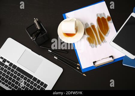 Un ordinateur portable, une tablette et une tasse de café retournée sur une table Banque D'Images