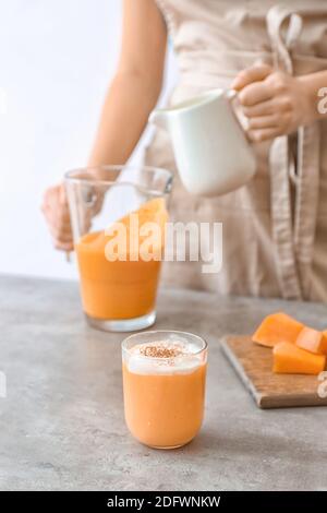 Femme préparant un délicieux smoothie à la citrouille à table Banque D'Images