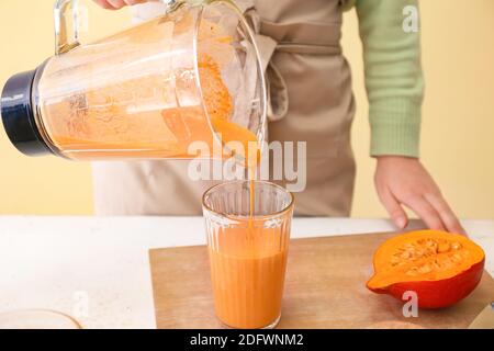 Femme préparant un délicieux smoothie à la citrouille à table Banque D'Images