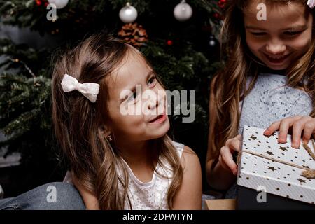 Gros plan rogné vue portrait de sœurs belle gaie gaie gaie filles passer des vacances de Noël et filles échanger des cadeaux à l'intérieur. Banque D'Images