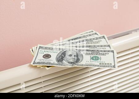 Billets en dollars sur radiateur, gros plan. Concept de saison de chauffage Banque D'Images