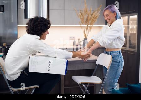 Un jeune couple heureux qui débarque la toute nouvelle console de jeu Sony PlayStation 5 chez lui. Moscou - novembre 28 2020. Banque D'Images