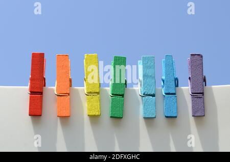 Sept épingles en bois multicolores, peintes dans les couleurs de l'arc-en-ciel, contre le ciel bleu. Banque D'Images