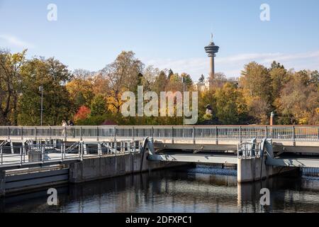 Passerelle au-dessus de Tammerkoski et de la tour d'observation de Näsinneula derrière le parc Wilhelm von Nottbeck aux couleurs automnales. Tampere, Finlande. Banque D'Images