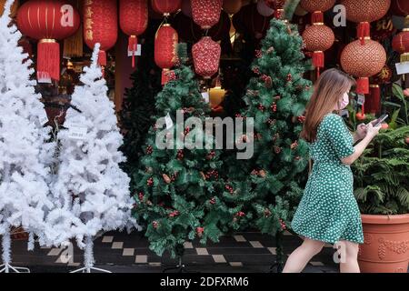 Kuala Lumpur, Malaisie. 29 novembre 2020. Une dame portant un masque de visage se promène devant un arbre de Noël à Kuala Lumpur.malgré l'impact de la pandémie de coronavirus qui nécessite une distanciation sociale, Kuala Lumpur ville encore illuminée par la décoration colorée de Noël. Credit: Faris Hadziq/SOPA Images/ZUMA Wire/Alay Live News Banque D'Images