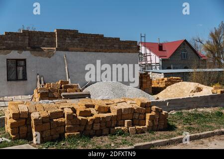 Une pile de briques se trouve devant la maison en cours de construction. Banque D'Images