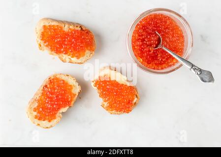 Caviar rouge et chanpe au beurre sur pain grillé à la baguette, fond en marbre blanc. Hors-d'œuvre russe traditionnel pour Noël, table du nouvel an Banque D'Images