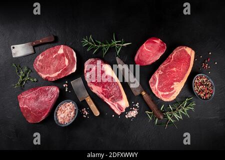 Plat de viande. Diverses coupes de viande, plat de dessus de lit grenaille avec des couteaux, sel, poivre, et herbes, sur un fond d'ardoise noire