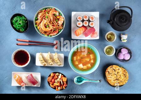 Nourriture japonaise, sushi, udon, soupe miso, thé, mochi etc., plan d'air à plat sur fond bleu Banque D'Images