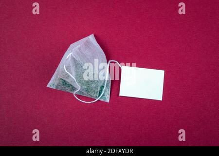 Teabag avec étiquette blanche. Vue de dessus, sur un arrière-plan rouge. Maquette. Banque D'Images